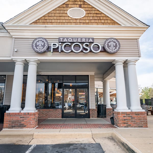 The exterior of Taqueria Picoso, a Mexican restaurant with a prominent sign and large glass doors.