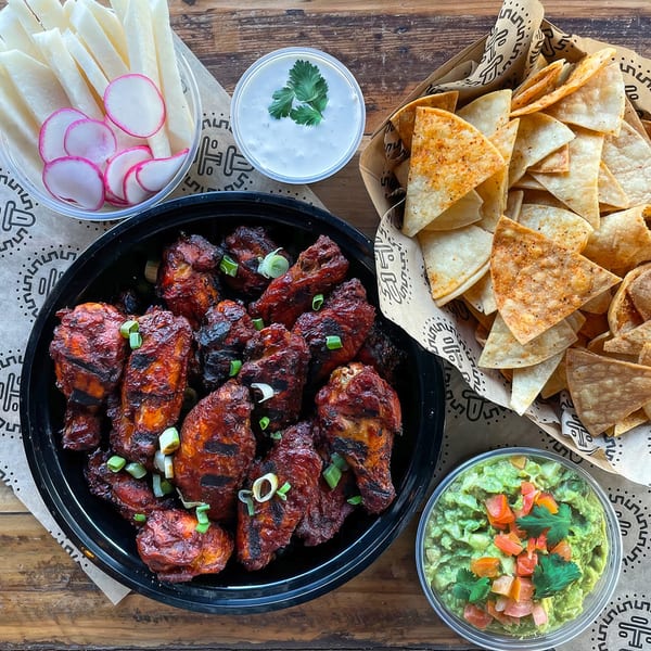 Taqueria Picoso's Mexican feast with grilled chicken wings, tortilla chips, guacamole, and jicama with radishes.