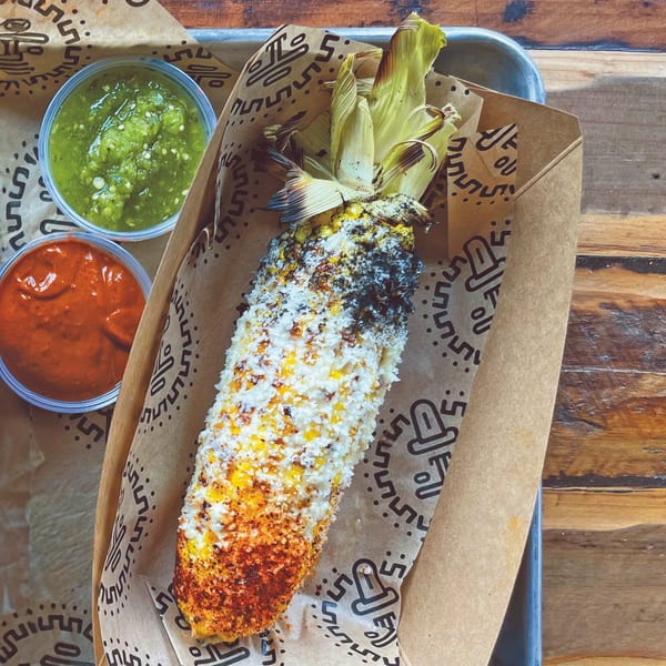 Elote with cotija cheese and chili powder, served with green and red salsa at Taqueria Picoso.