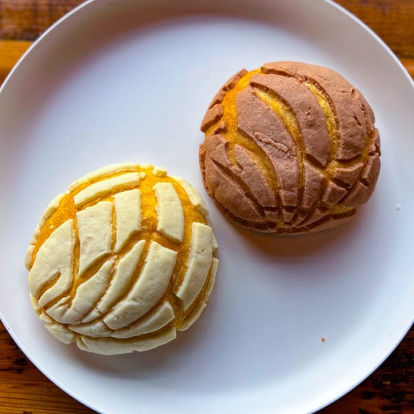 Two Mexican conchas, one light and one dark, on a white plate at Taqueria Picoso.