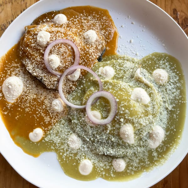 Two enchiladas, one with red sauce and one with green sauce, topped with cheese and onions.