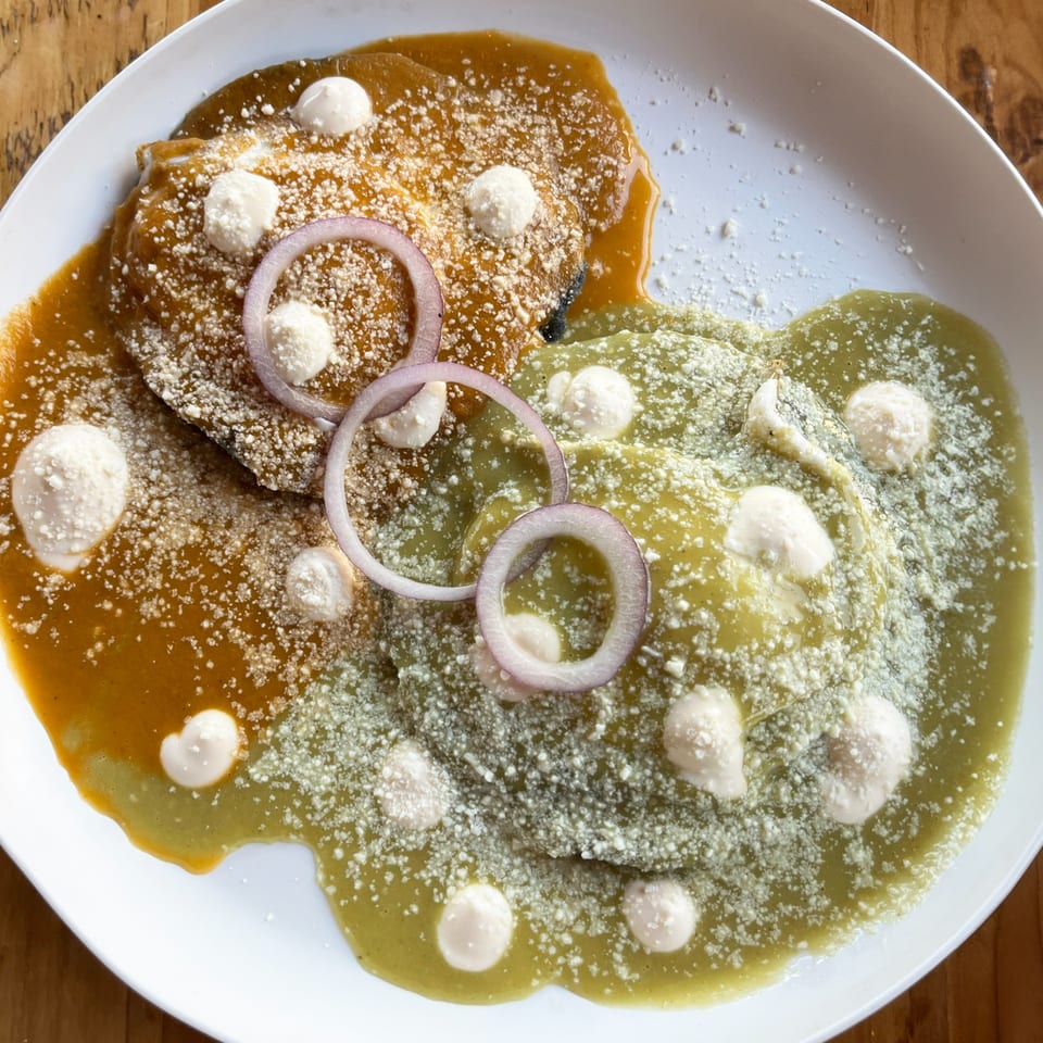 Two enchiladas, one with red sauce and one with green sauce, topped with cheese and onions.